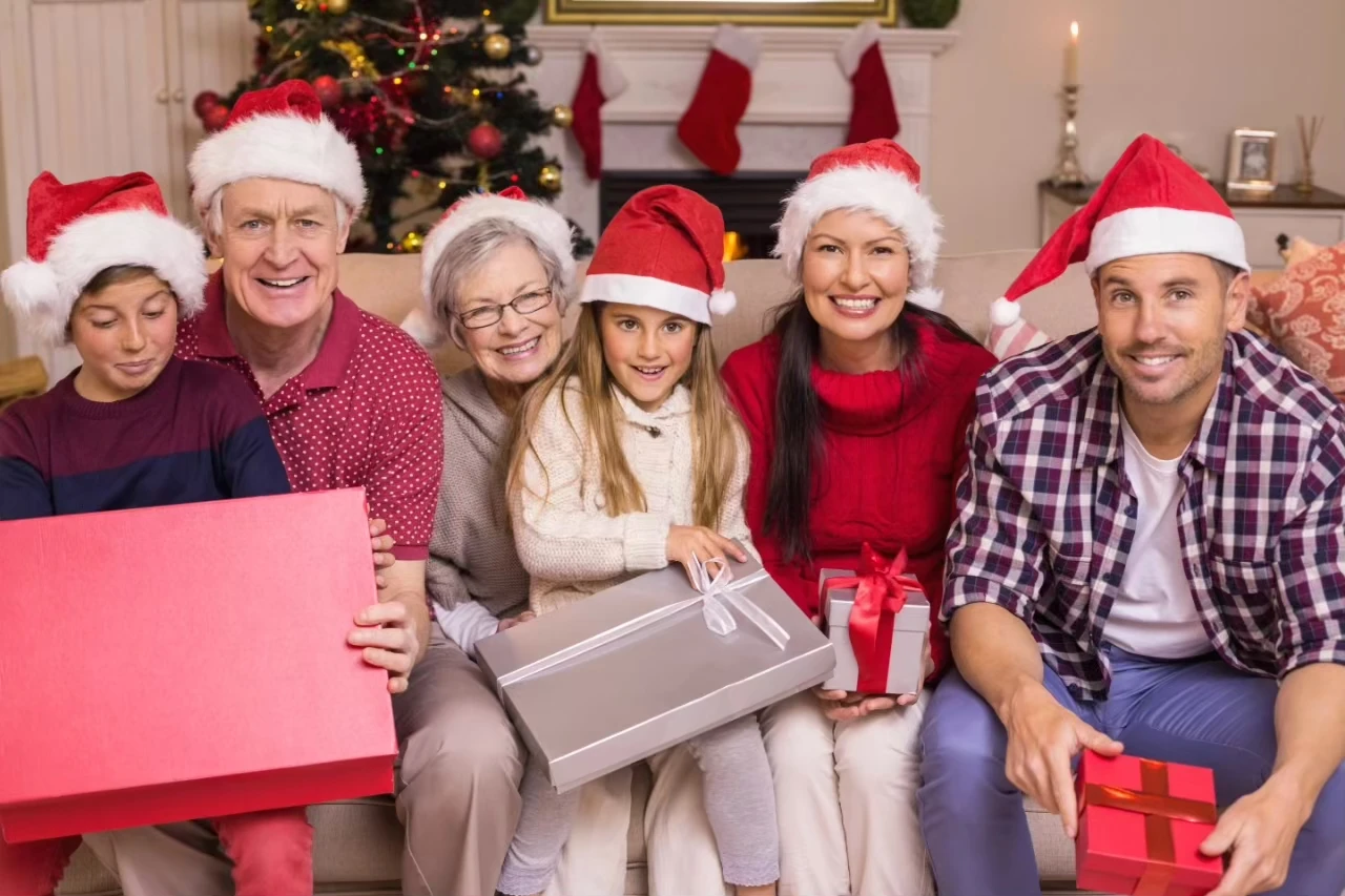 Drei Generationen mit Weihnachtsmützen, Geschenken und Weihnachtsdeko
