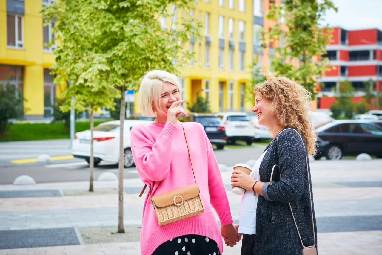 zwei Frauen in der Straße halten Hände und lachen ausgelassen