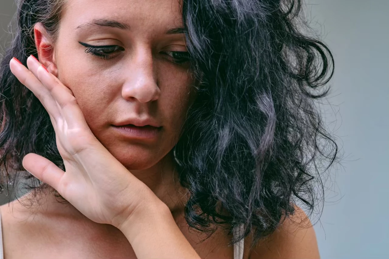Frau hält sich eine Wange mit der Hand
