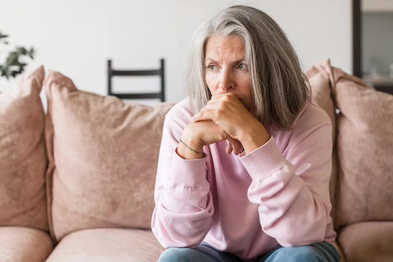 Frau sitzt nachdenklich auf dem Sofa