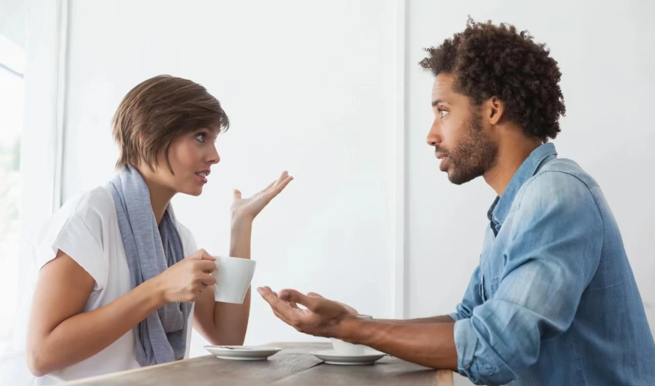 Frau und Mann sitzen sich an einem Tisch gegenüber und diskutieren