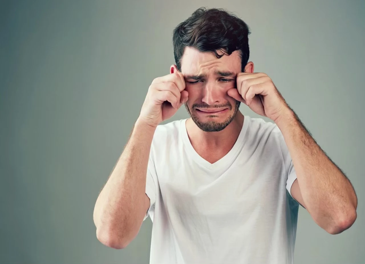 Mann macht ein jammerndes Gesicht und reibt sich mit den Fäusten die Augen