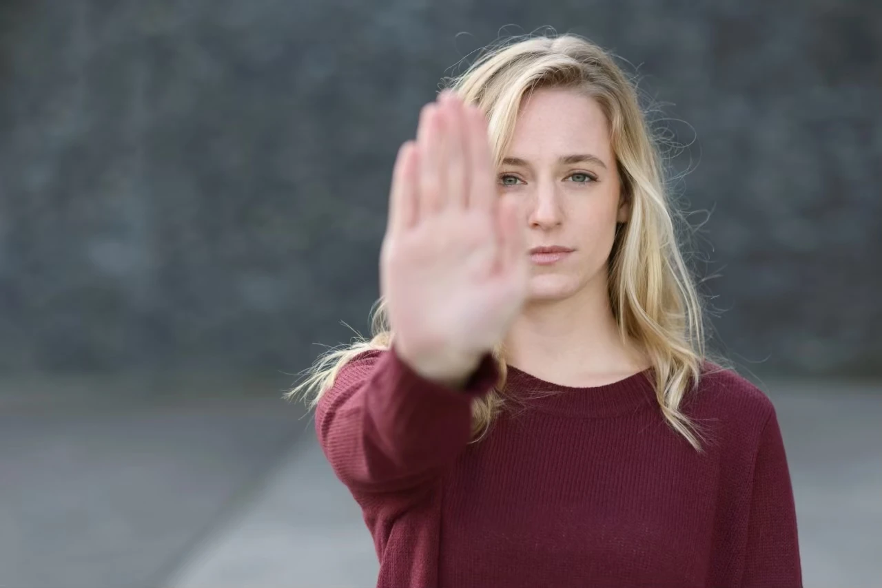 Selbstbewusste Frau streckt Hand abwehrend Richtung Kamera