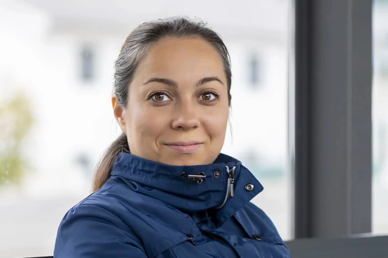 Frau mit braunem Zopf und blauer Jacke mit hohem Kragen