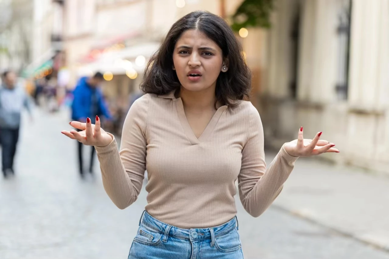 Frau mit ungehaltenem Gesichtsausdruck hebt fragend die Hände