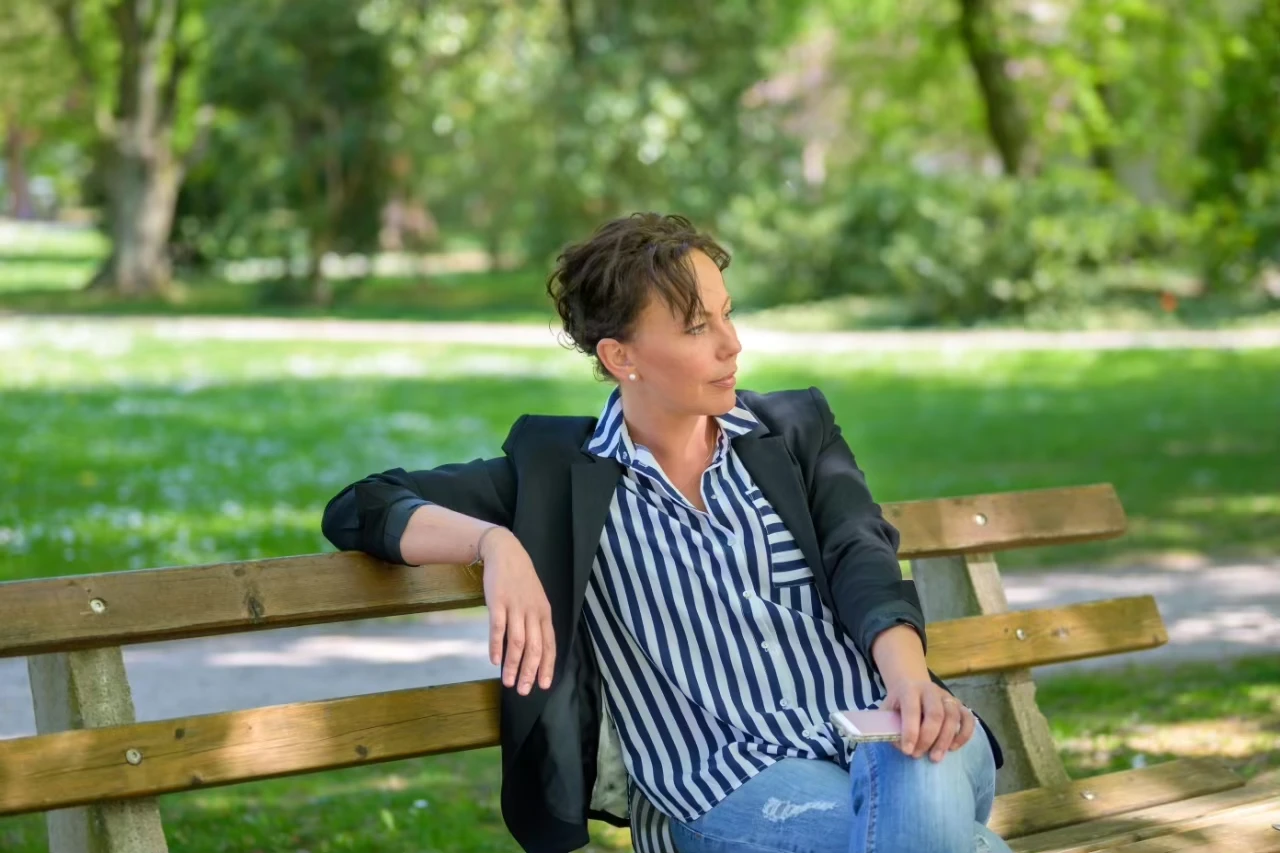 Frau sitzt wartend auf einer Parkbank