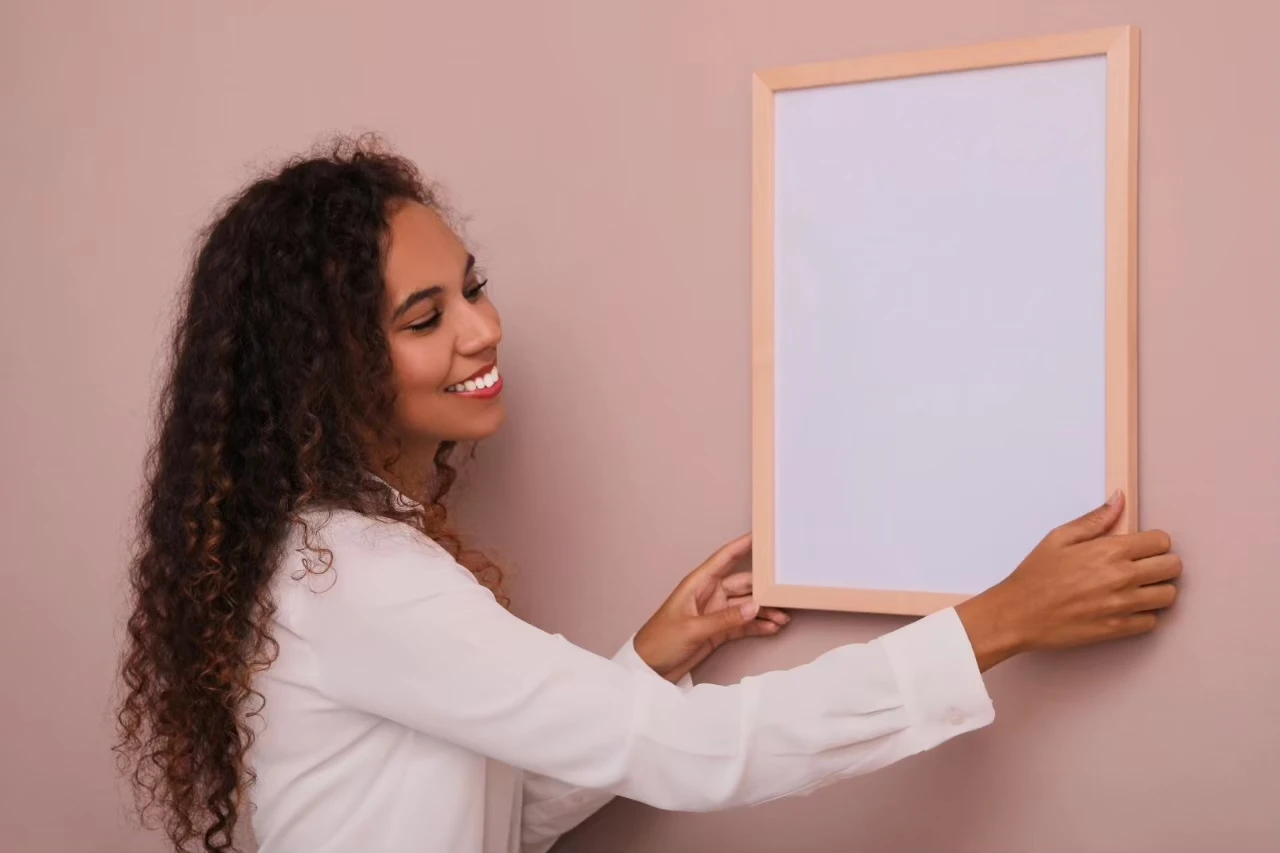 Frau hängt neuen Rahmen an die Wand