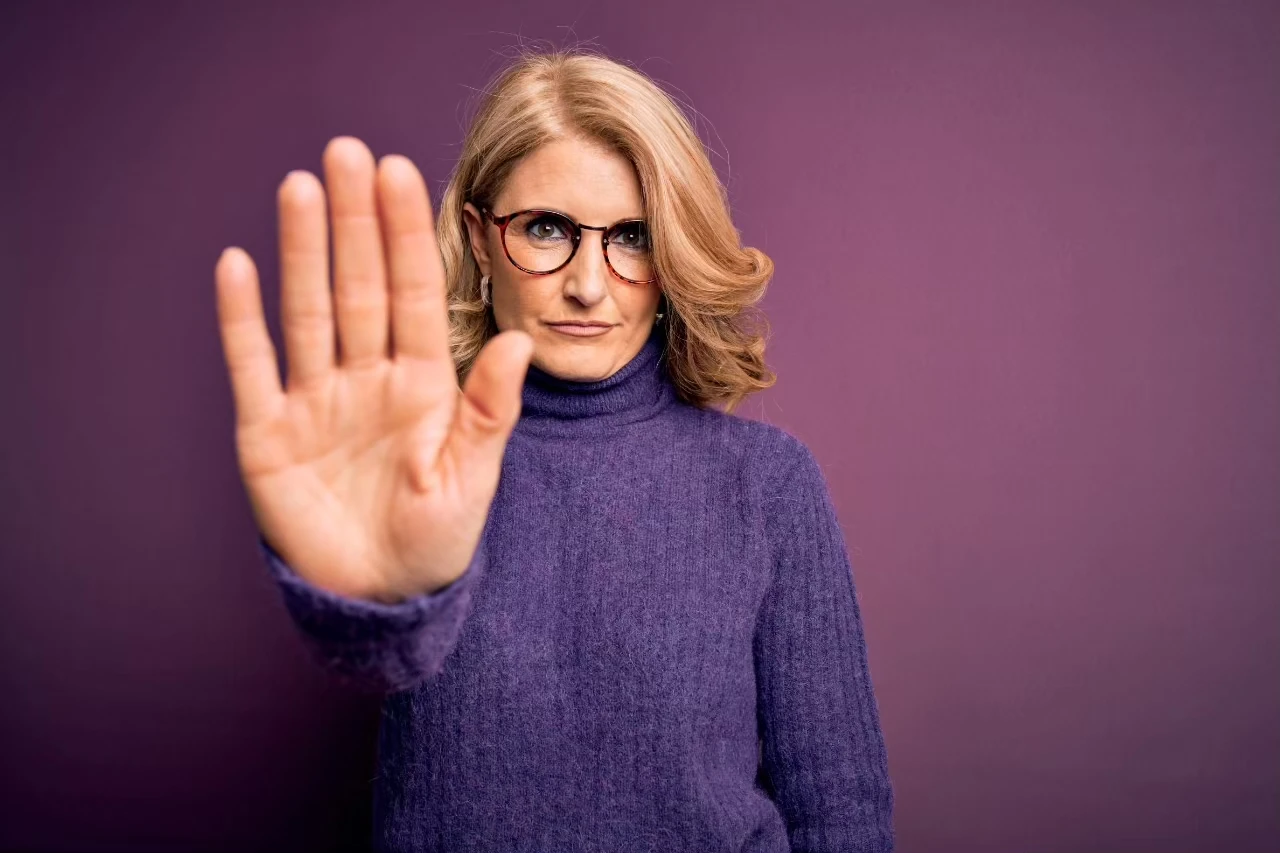 Frau hält eine Hand abwehrend in die Kamera