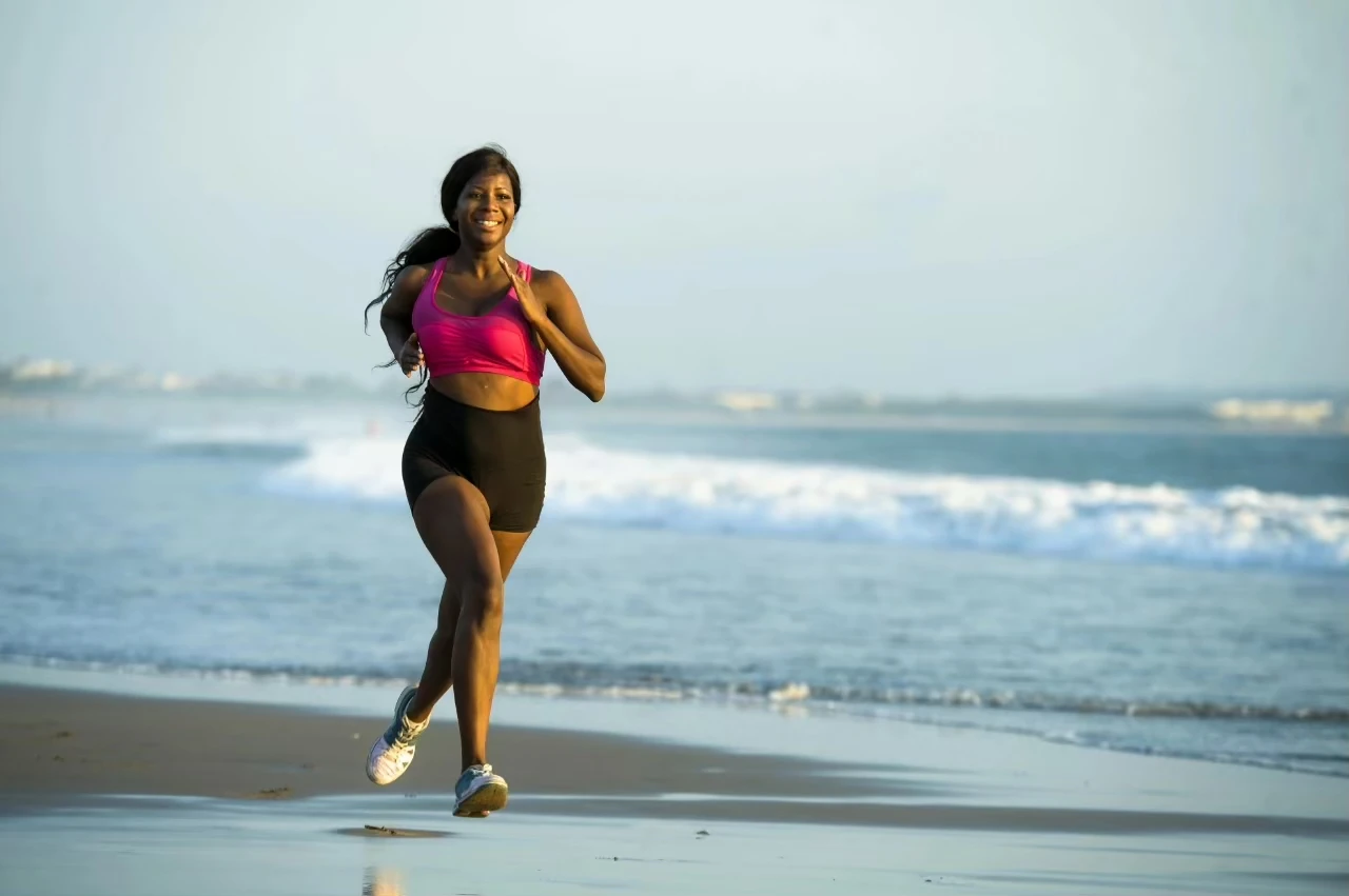 Frau joggt lächelnd am Strand entlang