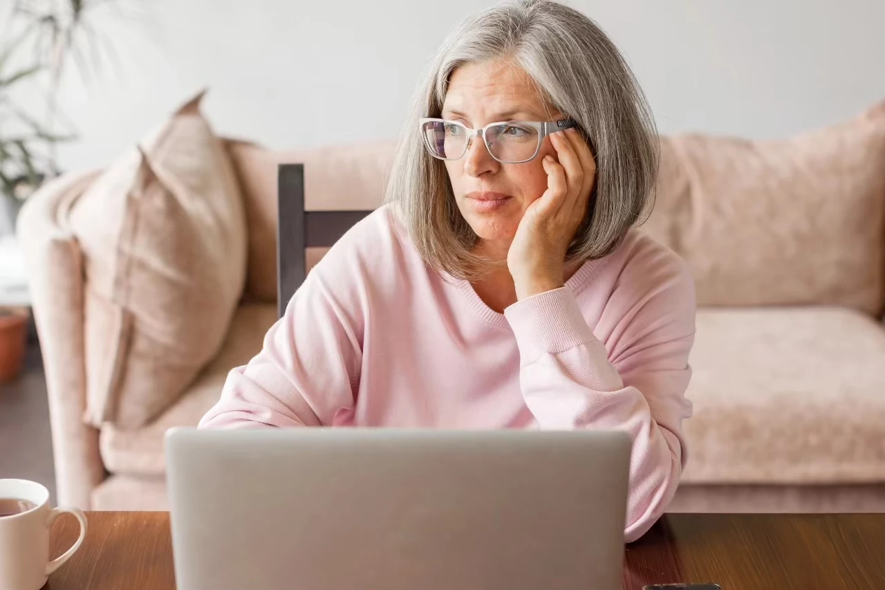Frau mit verfrüht grauen Haaren sitzt vor einem Laptop