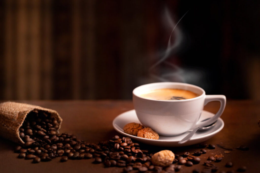 Eine dampfende Tasse Kaffee vor gemütlich-dunklem Hintergrund