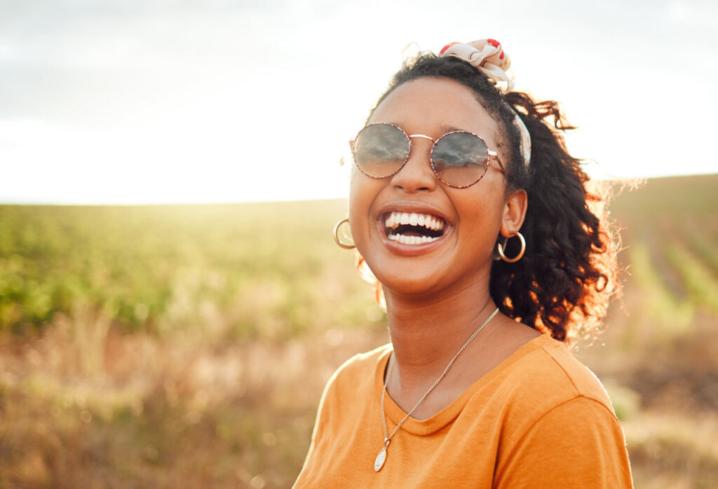 Frau mit Sonnenbrille lacht in die Kamera